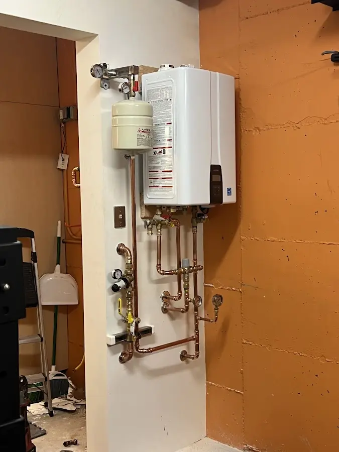 Plumbing technician inspecting water heater connections in Rowley